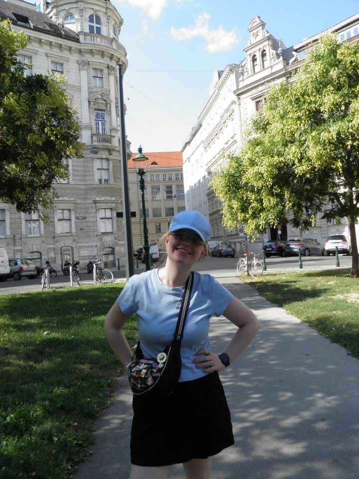 Moi à Vienne, en casquette et t-shirt bleus, sur une place bordée d'immeubles anciens
